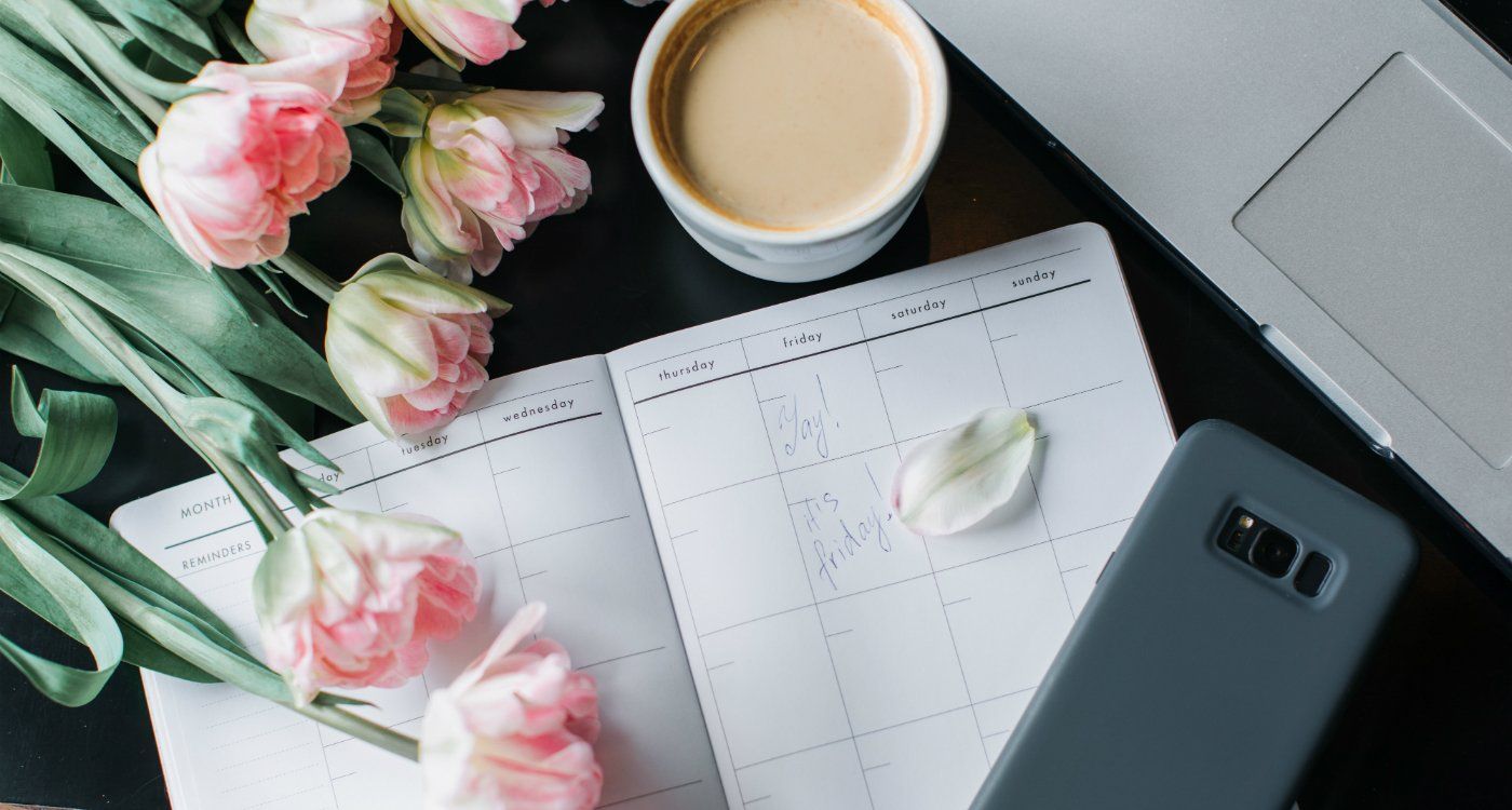 An Organised Desk With A Journal And Flower On It