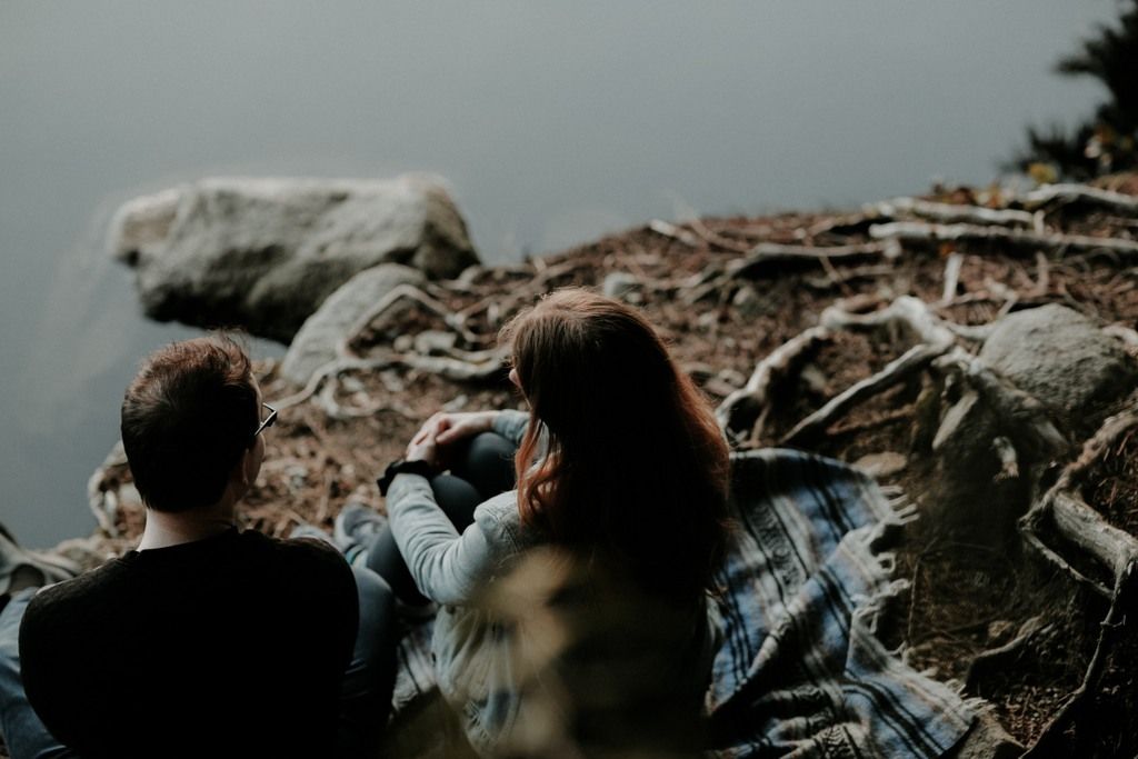 A Young Boy And Girl Sitting Near A Water Body Talking Generously